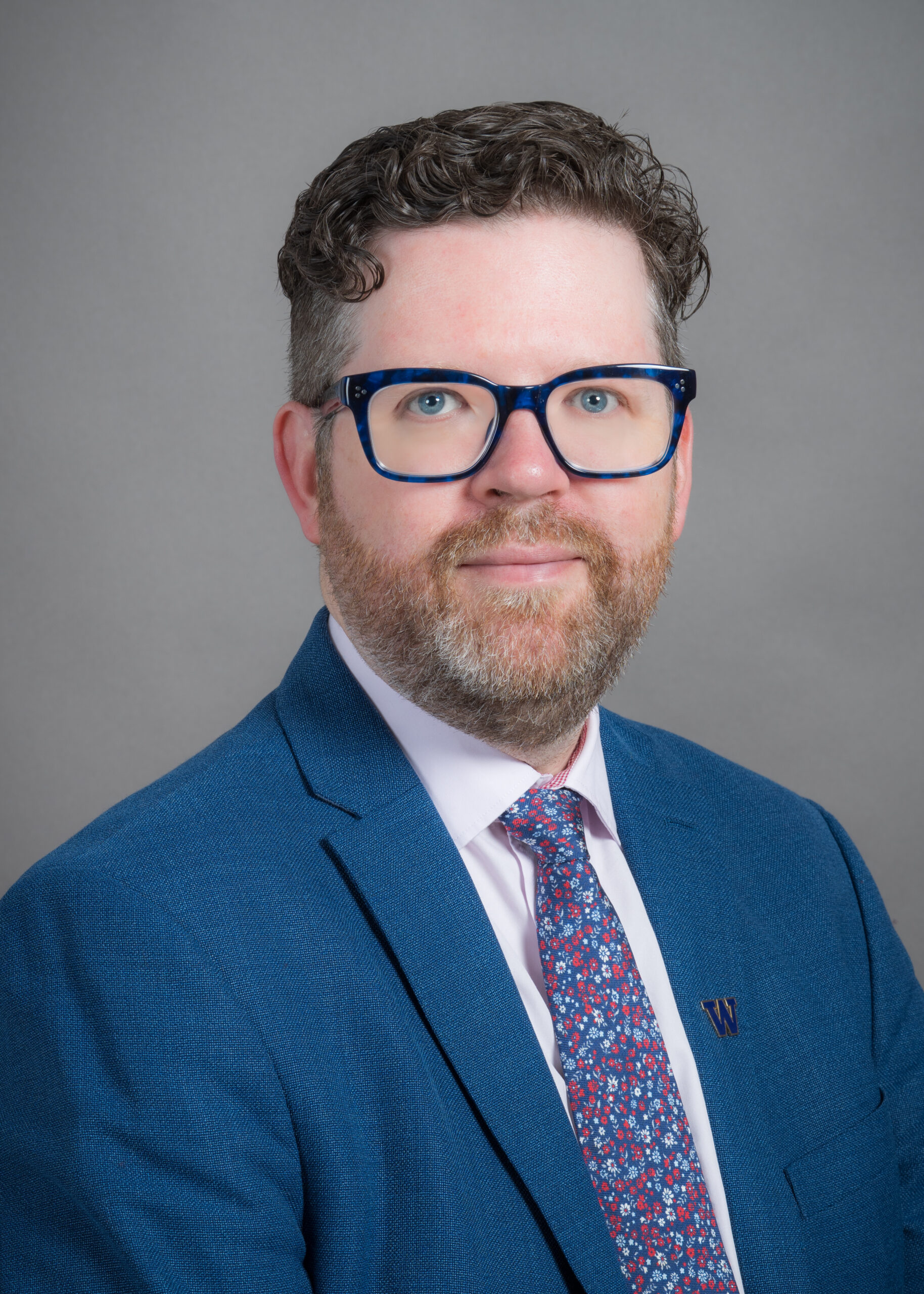 Photo of Pat wearing glasses and a sharp suit